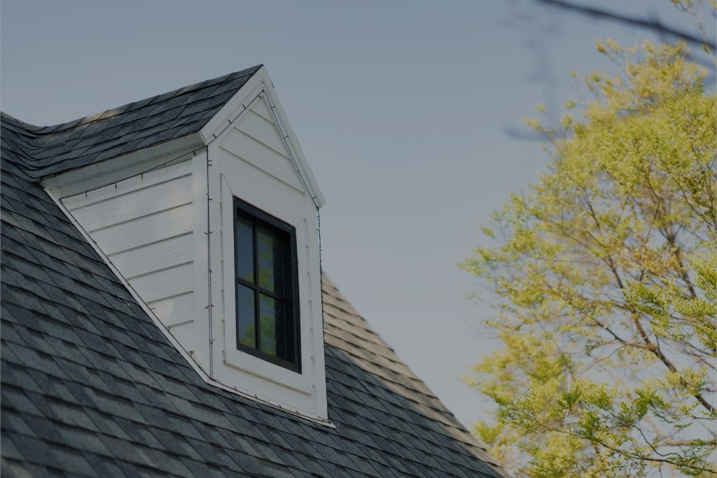 Dormer window on an asphalt shingle roof with clean white siding.