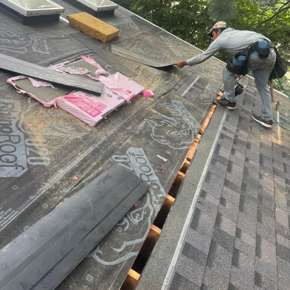 A roofing installer securing underlayment and preparing shingle placement.