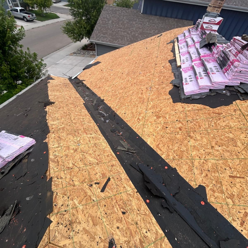roof tear-off showing exposed plywood decking during roofing replacement
