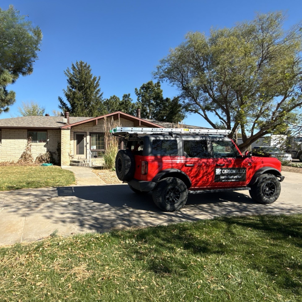 Carbon Black storm restoration vehicle parked in front of a residential home during roof inspection