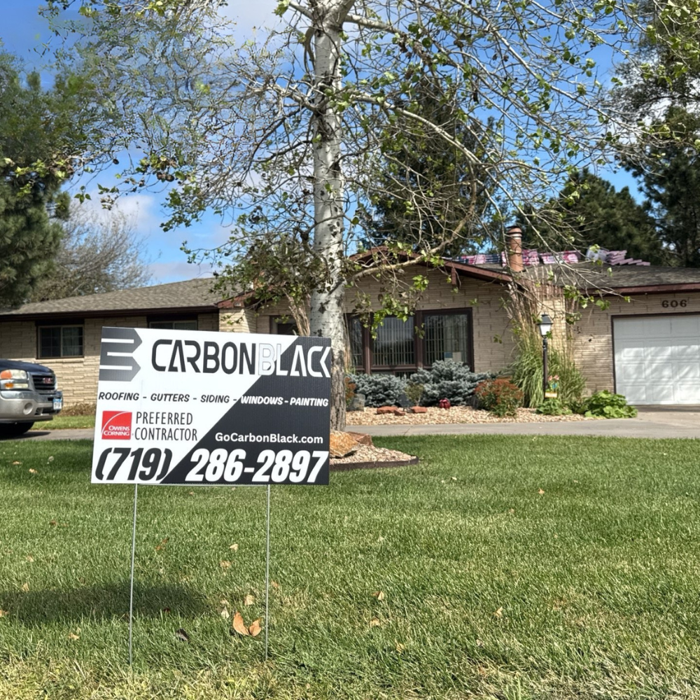 A CarbonBlack roofing yard sign placed in front of a customer’s home, indicating an active roof replacement project.